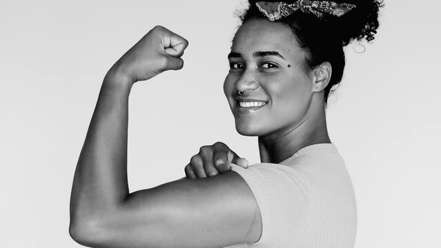 Empowered Young African American Female Demonstrating Strength – Black and White Image of Latina Flexing Arm with 'We Can Do It' Pose, Looking at Camera