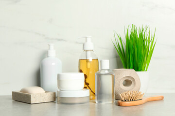 Fototapeta na wymiar Brush and personal care products on gray table near white marble wall