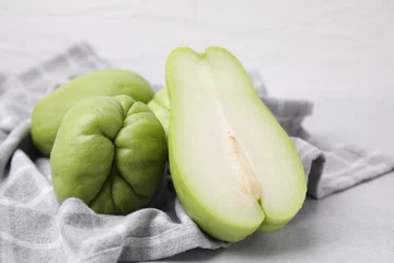 Tuinposter Cut and whole chayote on gray table, closeup © New Africa
