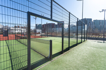 Obraz premium Landscaped areas of a residential development with a tennis court with high Plexiglas and metal fences