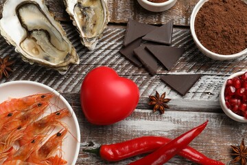 Natural aphrodisiac. Different food products and heart model on wooden table, flat lay