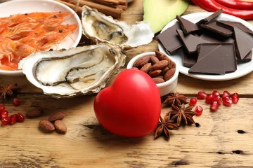 Deurstickers Natural aphrodisiac. Different food products and heart model on wooden table, closeup © New Africa