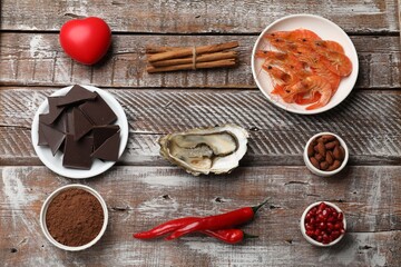 Natural aphrodisiac. Different food products and heart model on wooden table, flat lay