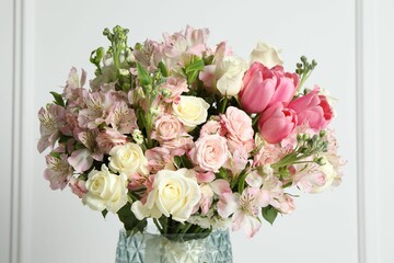Beautiful bouquet of fresh flowers in vase near white wall