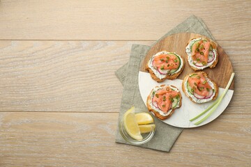 Fototapeta na wymiar Tasty canapes with salmon served on wooden table, top view. Space for text