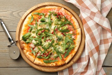 Board with delicious vegetarian pizza on wooden table, top view