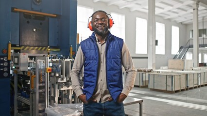 Serious thoughtful African-American employee male standing during work process. Graceful stylish handsome elegant bearded man smiling chuckling blinking standing in pleased pose.