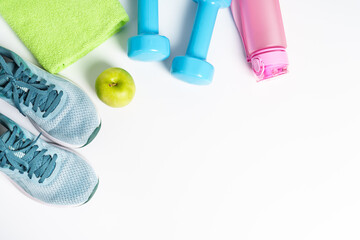 Sneakers, dumbbells, green apple and bottle of water isolated on white background. Flat lay image.
