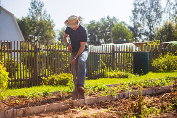 The farmer digs the soil in the vegetable garden. Preparing the soil for planting vegetables. Gardening concept. Agricultural work on the plantation