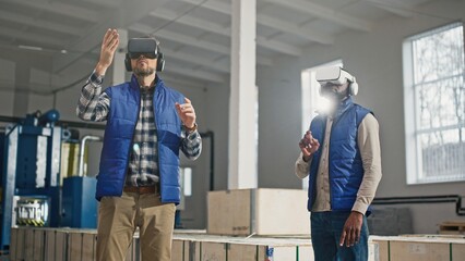 Multi-ethnic co-workers using Virtual Reality headsets for possible improvements in production. Digital device helping people in modern jobs. Moving hands while using VR to learn new concept.