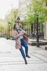 Beautiful young woman having fun with bagel outdoor on the street
