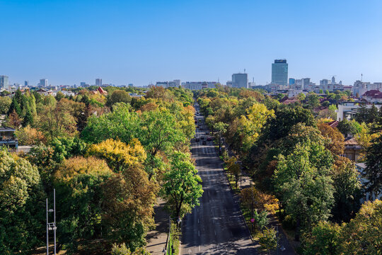 Panoramic city view with park and modern buildings in the background under a clear blue sky, Bucharest, Romania