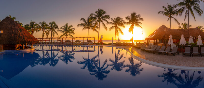 View of sunrise and palm tree reflections in hotel pool near Puerto Morelos, Caribbean Coast, Yucatan Peninsula, Mexico