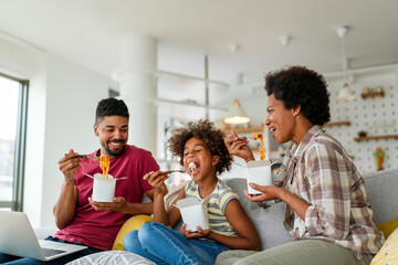 Happy african family eating at living room and enjoying time together. Home delivary takeaway food - 780626160