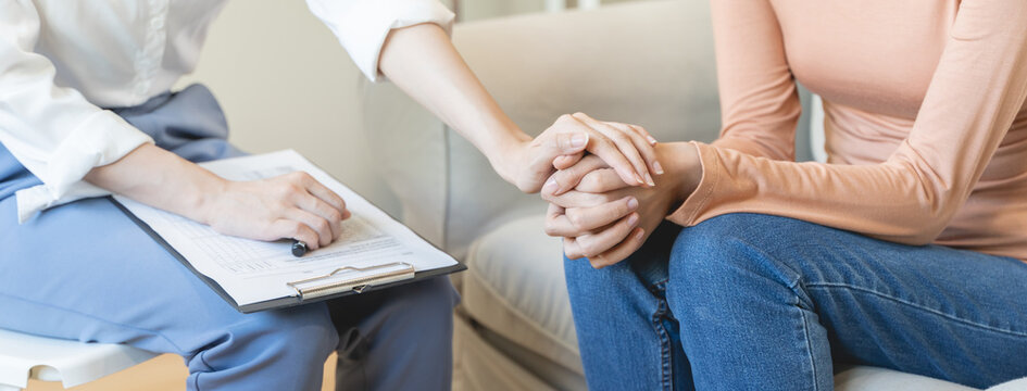 psychologist touching hands and encouraging stressed woman have by about mental health problem - Powered by Adobe