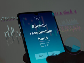 An investor analyzing the socially responsible bond etf fund on a screen. A phone shows the prices of Socially responsible bond