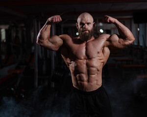 Caucasian bald man posing in the gym.