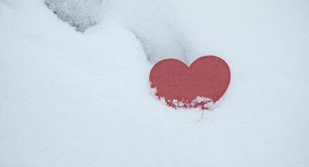 Red heart on snow background at winter.