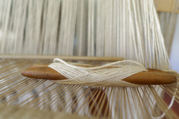 A shuttle for textile work with string under tension.
