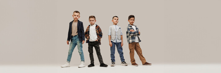 Banner. Cool attitude little boys, elementary pupils posing against grey studio background with...