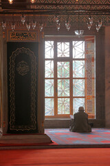 Istanbul, Türkiye, a muslim man sitting and praying in front of the window in a mosque during the...
