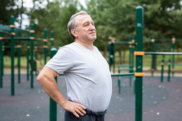 Elderly man doing gymnastics on an outdoor sports ground