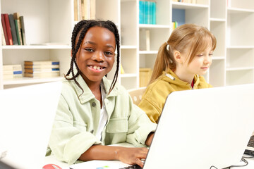 Smiling African American boy typing on the laptop while studying in computer science class