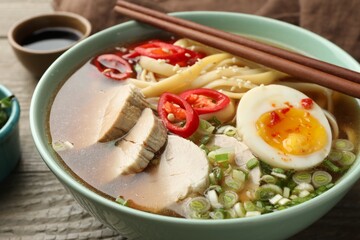 Delicious ramen in bowl on wooden table, closeup. Noodle soup