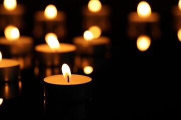 Burning candles on surface in darkness, closeup. Space for text