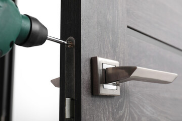 Repairing door handle with electric screwdriver indoors, closeup - obrazy, fototapety, plakaty