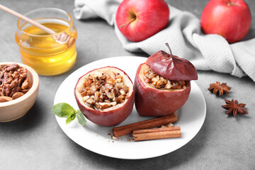 Fototapeta na wymiar Tasty baked apples with nuts, honey and spices on gray table