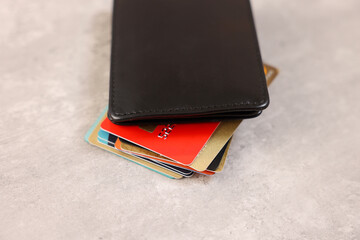 Many different credit cards and leather wallet on grey table, closeup