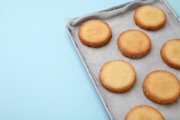 Tray with tasty sweet sugar cookies on light blue background, closeup. Space for text