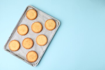 Tray with tasty sweet sugar cookies on light blue background, top view. Space for text
