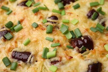 Tasty sausage casserole with green onions as background, closeup