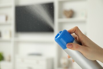 Woman spraying air freshener at home, closeup. Space for text