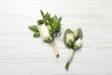 Wedding stuff. Stylish boutonnieres on white wooden table, top view