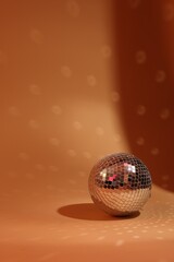 Shiny disco ball on orange background. Space for text