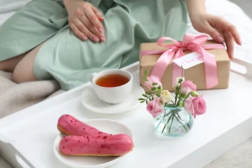  Tasty breakfast served in bed. Woman with gift box, tea, eclairs, flowers and I Love You card at home, closeup © New Africa