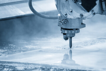The multi axis abrasive waterjet cutting machine cutting the metal plate in the light blue scene.
