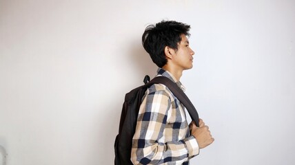 side view of happy young handsome Asian male student carrying bag isolated on white background