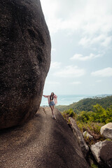 Woman stands confidently on a massive rock formation, overlooking the landscape below