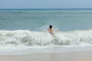 Woman splashes through the frothy waves at the beach