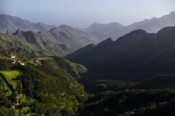 Evening light bathes a mountainous terrain, casting shadows and highlighting the verdant hills. Tenerife, Spain