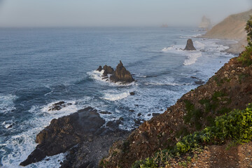 Dawn breaks over a tranquil coast with rocky cliffs and undulating waves, creating a peaceful seascape