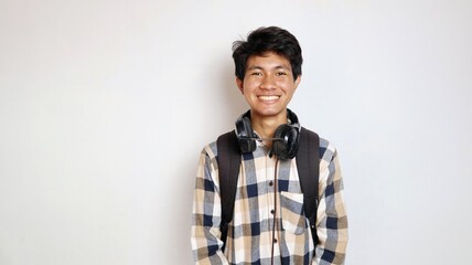 happy young asian male student wearing earphones and holding bag