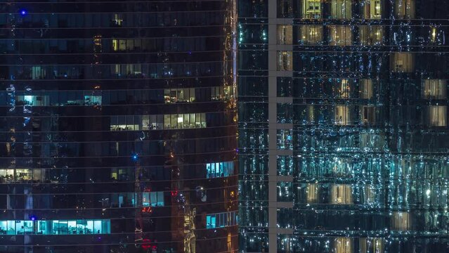 Office and residential buildings windows illuminated at night timelapse. Glass architecture, corporate building at evening with glowing lights. Reflections on skyscrapers surface