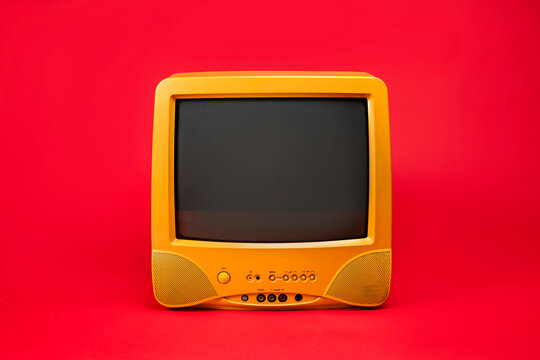 Old yellow television set with blank black screen Isolated on a red background