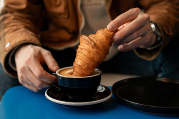 Man having delicious breakfast with croissant and coffee