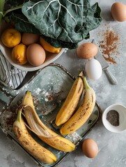 Banana bread in a baking dish with sliced bananas on top, surrounded by eggs, bananas, and a cup of coffee on a kitchen counter.